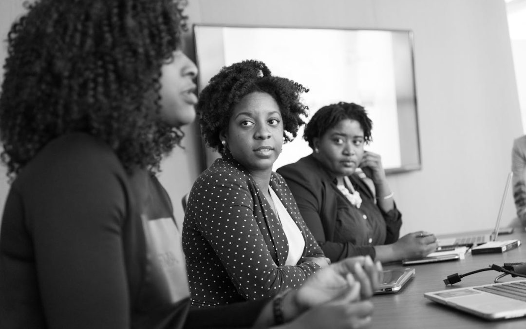 black and white image of three women at a table in a meeting