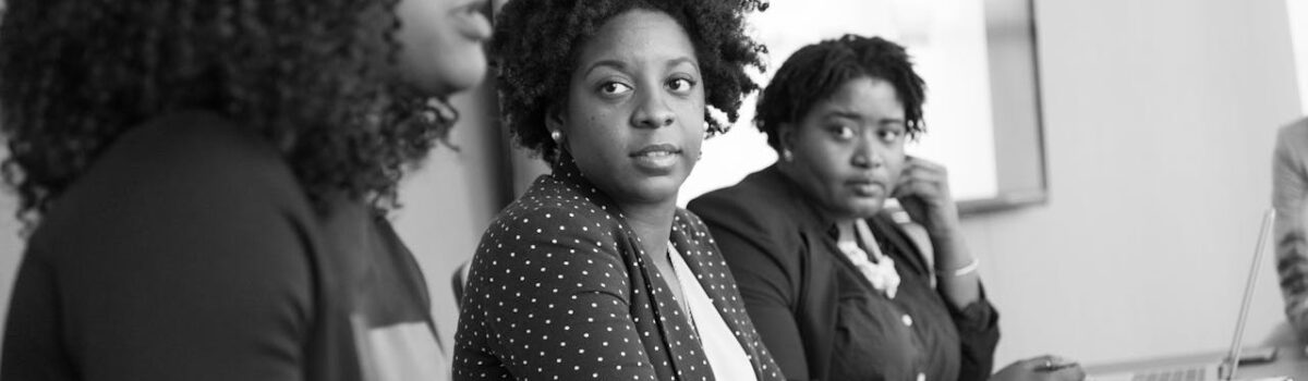 black and white image of three women at a table in a meeting