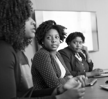 black and white image of three women at a table in a meeting