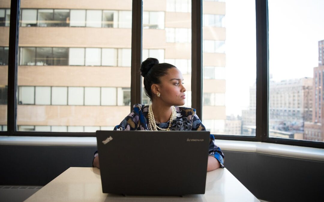 Woman with laptop at table with window behind her. Are you empowering or enabling. How to lead with accountability and respect.