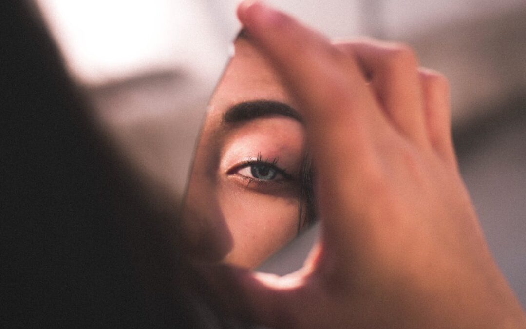 woman looking in a broken mirror shard; leadership as self-development